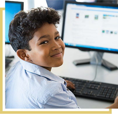 little boy smiling while working at his computer